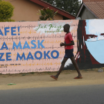 Boy walks past mask grafiti in Malawi